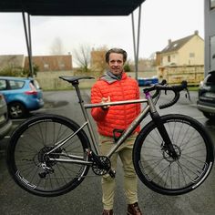 a man standing next to a bike in a parking lot