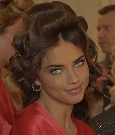 a woman in a red dress is smiling at the camera with her hair pulled back