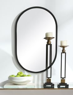 a table with a mirror and two candles on it next to a bowl of apples