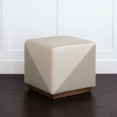 a square foot stool sitting on top of a hard wood floor next to a white wall