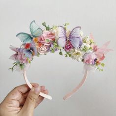 a hand holding a flower crown with butterflies on it