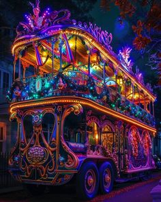 a brightly lit double decker bus driving down the street at night with christmas lights on it's roof