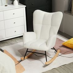 a white rocking chair sitting on top of a rug next to a bed and dresser