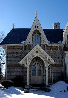 an old brick house with a blue roof and white trim on the front door is covered in snow