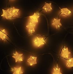 a string of yellow paper stars on a black background with lights strung from them to look like they are floating in the air