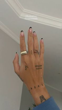 a woman's hand with tattoos on it and her fingers in the air,