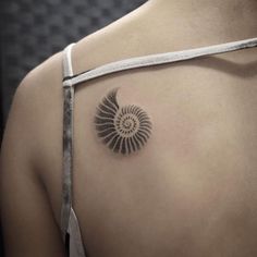 a woman's shoulder with a tattoo on it that has an ammonet shell