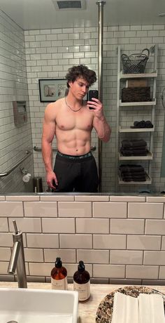 a shirtless man taking a selfie in the bathroom mirror with his cell phone