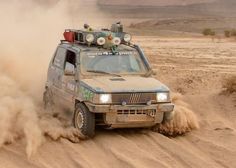 an off - road vehicle is driving through the desert with dust coming from its tires