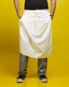 a man with an apron on standing in front of a yellow background