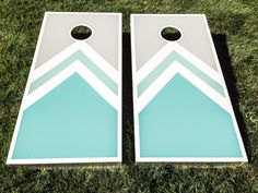 two white and blue cornhole boards sitting in the grass