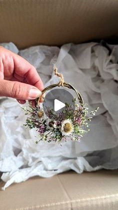 someone is holding a ring with flowers in it