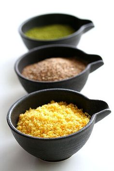 three black bowls filled with different types of food on top of a white countertop