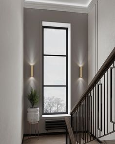 the stairs are lined with black railings and white walls, along with a potted plant