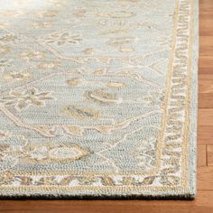 a light blue and beige rug with an ornate design on the bottom, sitting on a wooden floor