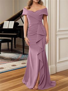 a woman standing in front of a piano wearing a purple dress