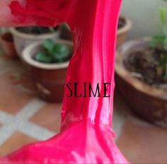 a pink plastic chair with the word slime written on it's leg in front of potted plants