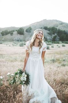 a woman in a white dress is standing in the middle of a field and smiling