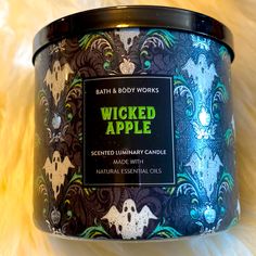 a candle that is sitting on some kind of furnishing material with the words,'bath & body works wicked apple scented luxury candle made with natural essentials '