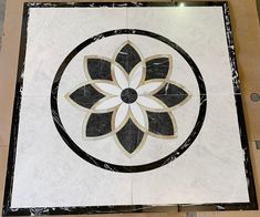 a black and white tile with a flower design on the floor in front of it