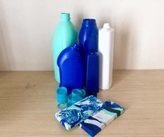 blue bottles and napkins are sitting on a wooden table next to a white wall