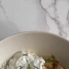 a white bowl filled with food on top of a marble counter