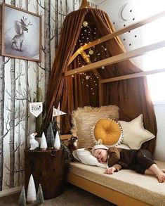 a young child sleeping on top of a bed in a room with trees and decorations