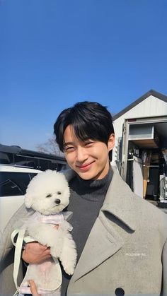 a man holding a white teddy bear in his right hand and smiling at the camera