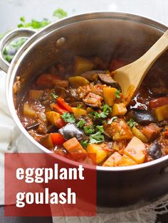 a pot filled with stew and vegetables on top of a white napkin next to a wooden spoon