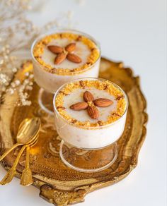 two desserts with nuts on top are sitting on a gold tray