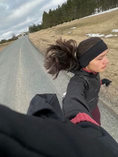 a woman riding on the back of a motorcycle down a road