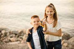 two young children standing next to each other near the water