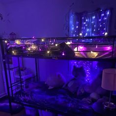 a bunk bed is lit up with purple and blue lights in the room, along with other decorations