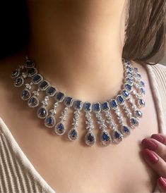 Add a touch of glamour and sophistication with this high quality necklace set in beautiful blue sapphire stones. The stones in this set bling and look close to the real thing. This set is sure to make heads turn!  It features an adjustable necklace and a pair of earrings and maangtika . It can be paired perfectly with both ethnic and western outfits. Length :14 Width:8 inches Adjustable length with a metal chain at the back Earrings length: 2.5 inches Each earring weighs: 12 gms  Closure: Pushba Bollywood Jewelry Necklaces, Blue Diamond Necklace Set, Bridal Diamond Jewellery Set, Necklace Set Indian Bridal Jewelry, Wedding Jewelry Indian, Blue Diamond Necklace, Diamond Necklace Wedding, Blue Jewelry Set, Emerald Green Necklace