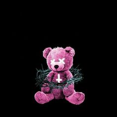 a pink teddy bear with barbed wire around it's neck and cross on its chest