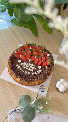 a chocolate cake with strawberries and marshmallows on top sits on a table