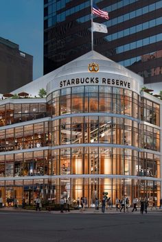 the exterior of starbucks's reserve in new york city, ny at night with people walking around