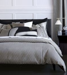 a bed with black and white comforter in a bedroom next to two lamps on either side of the bed