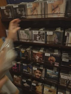 a woman is looking at cd's on the shelves in a music store,