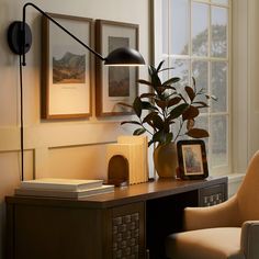 a desk with a chair, lamp and pictures on the wall in front of it