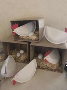 three cardboard boxes with paper plates and chickens in them