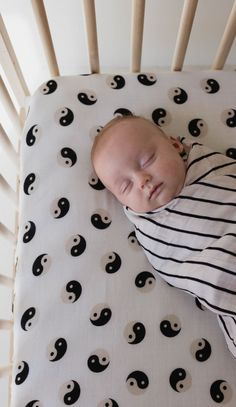 a baby sleeping in a crib with black and white designs