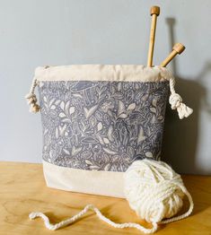 a crocheted ball of yarn next to a knitting needle and bag on a table