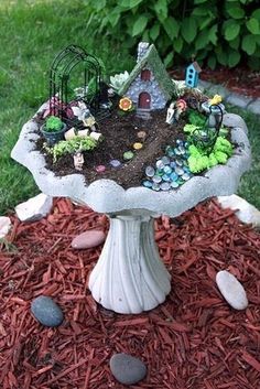 a small garden with rocks and plants in the center on top of a birdbath