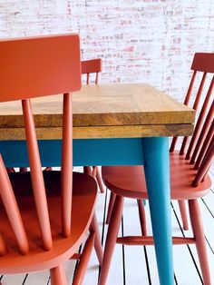 three chairs and a table in front of a brick wall with wood planks on the floor