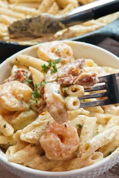 a fork in a bowl full of pasta with shrimp and parmesan cheese on top