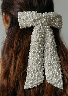 a woman with long hair wearing a white pearled bow