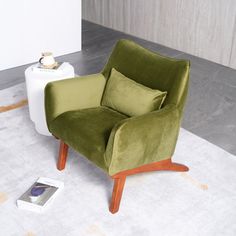 a green chair sitting on top of a white rug next to a phone and lamp