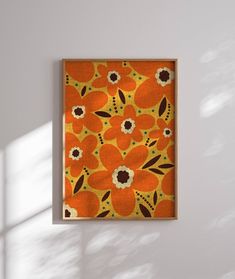 an orange and black flowered painting hanging on a wall