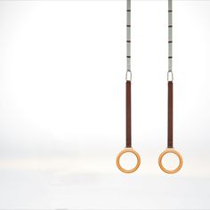 two pairs of wooden rings hanging from hooks in the air, with one being held by an o - ring